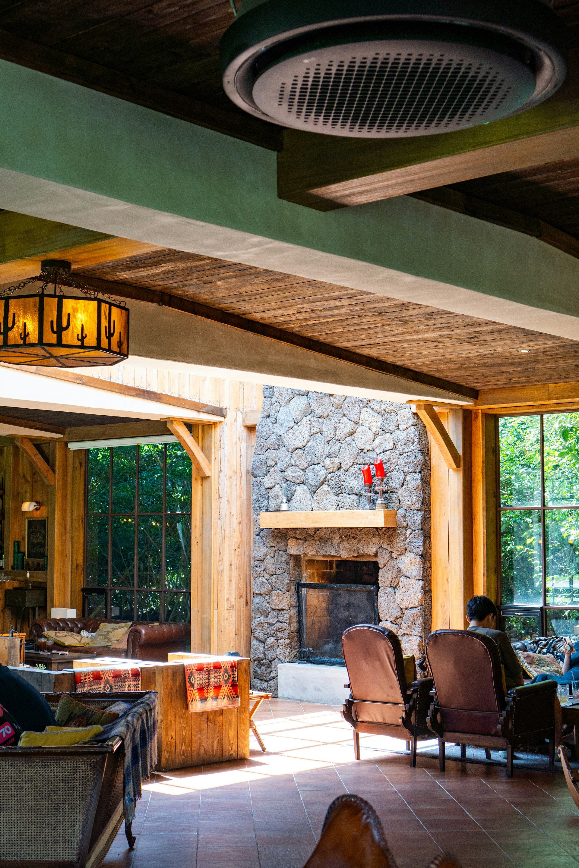 Cozy rustic living room with warm wooden beams and a stone fireplace in Casa Rural La Estación de Archidona.