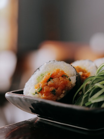 Close-up of a vibrant sushi platter with colorful rolls and fresh garnishes on a dark ceramic plate