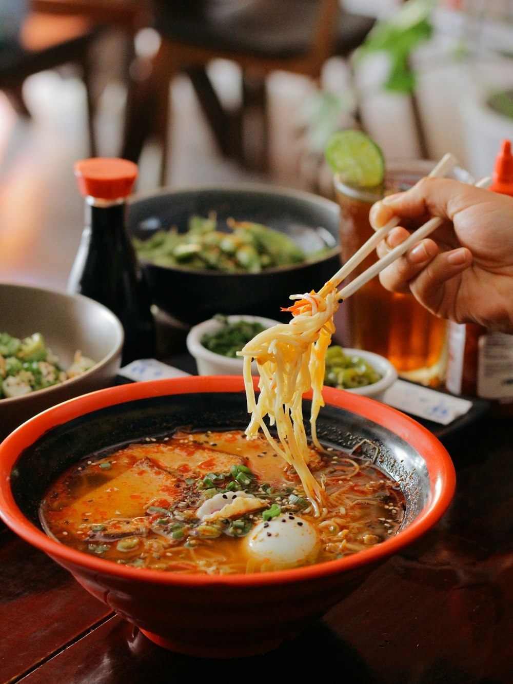 a person holding chopsticks over a bowl of soup