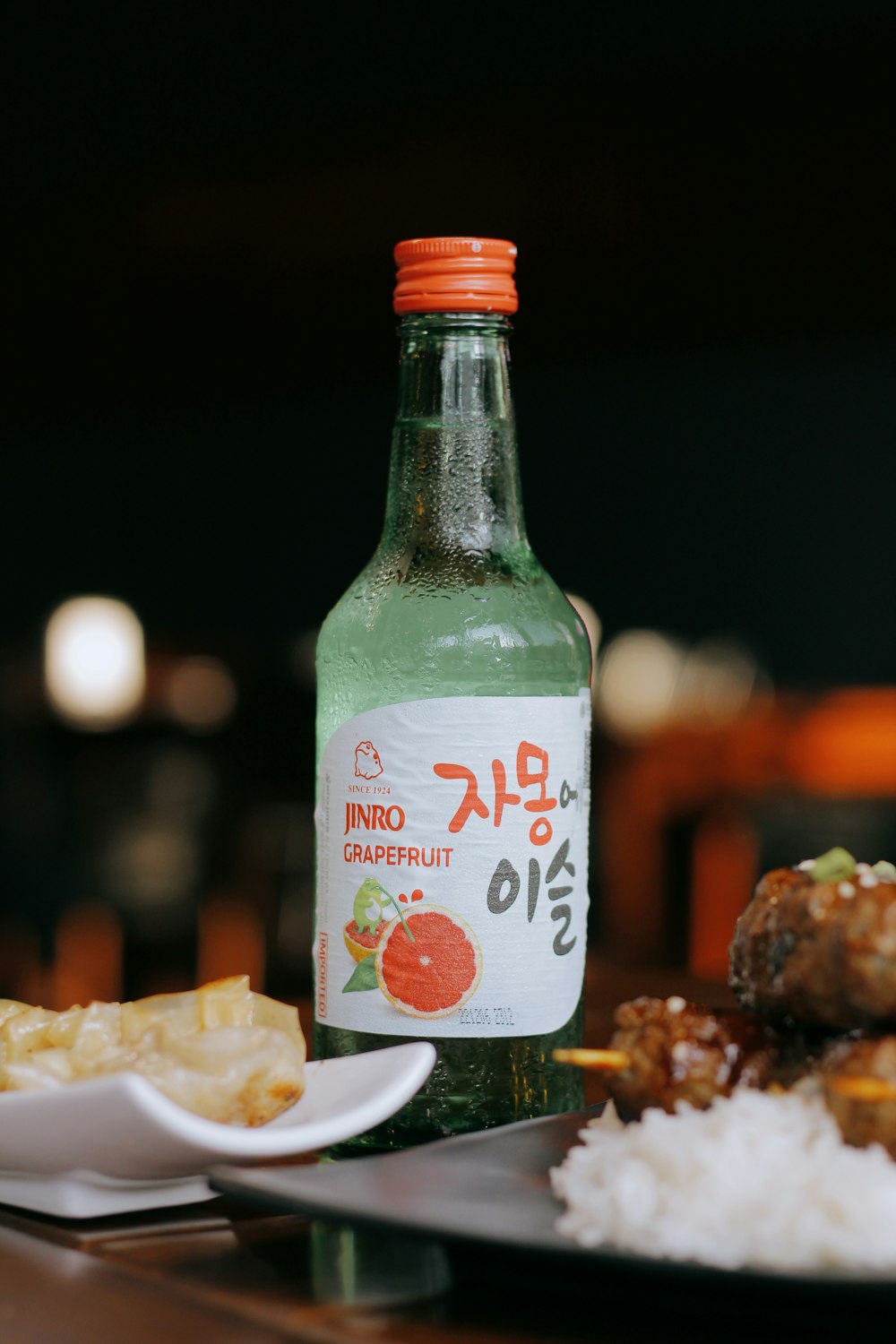 Una botella de refresco sentada junto a un plato de comida
