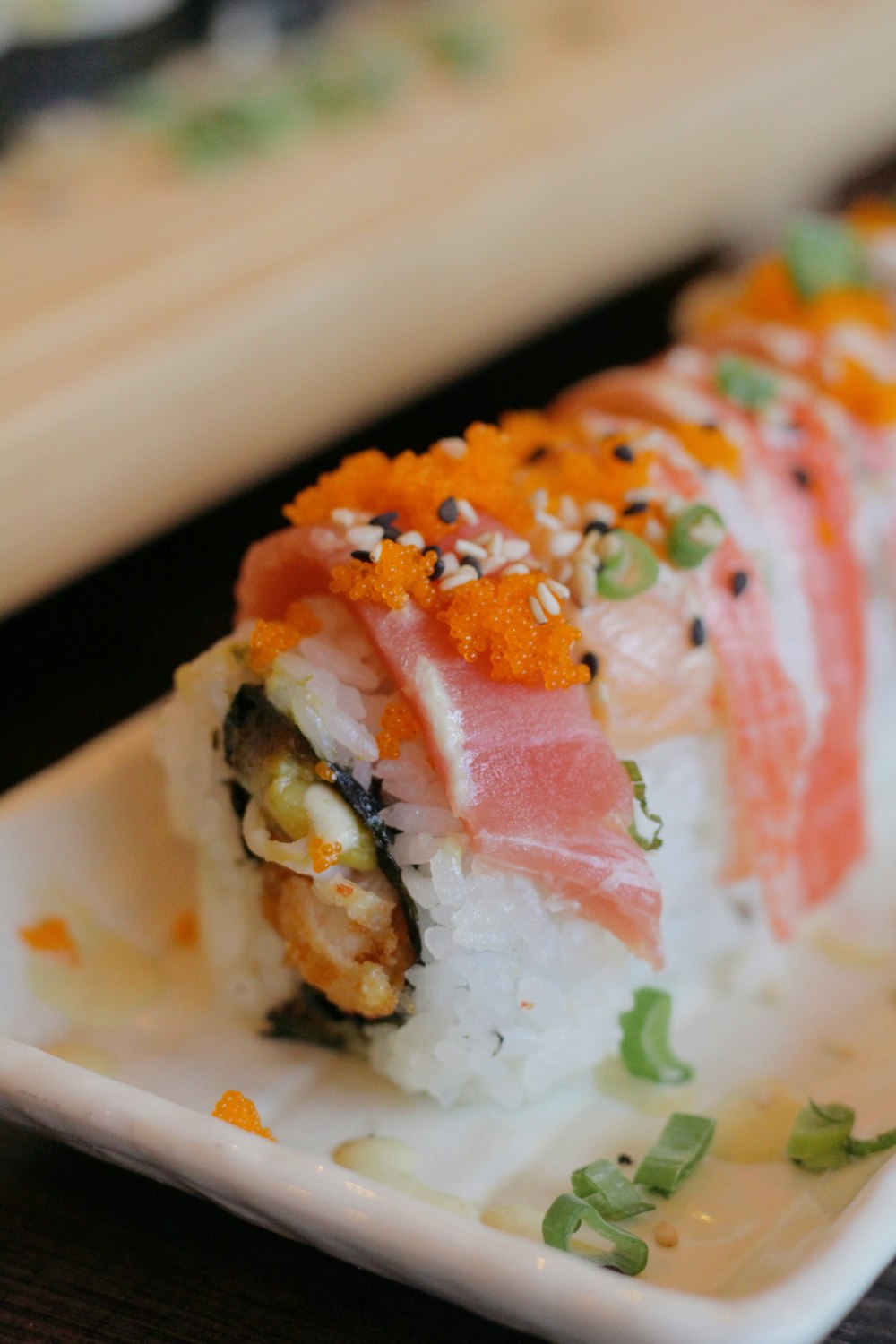 a white plate topped with sushi on top of a wooden table