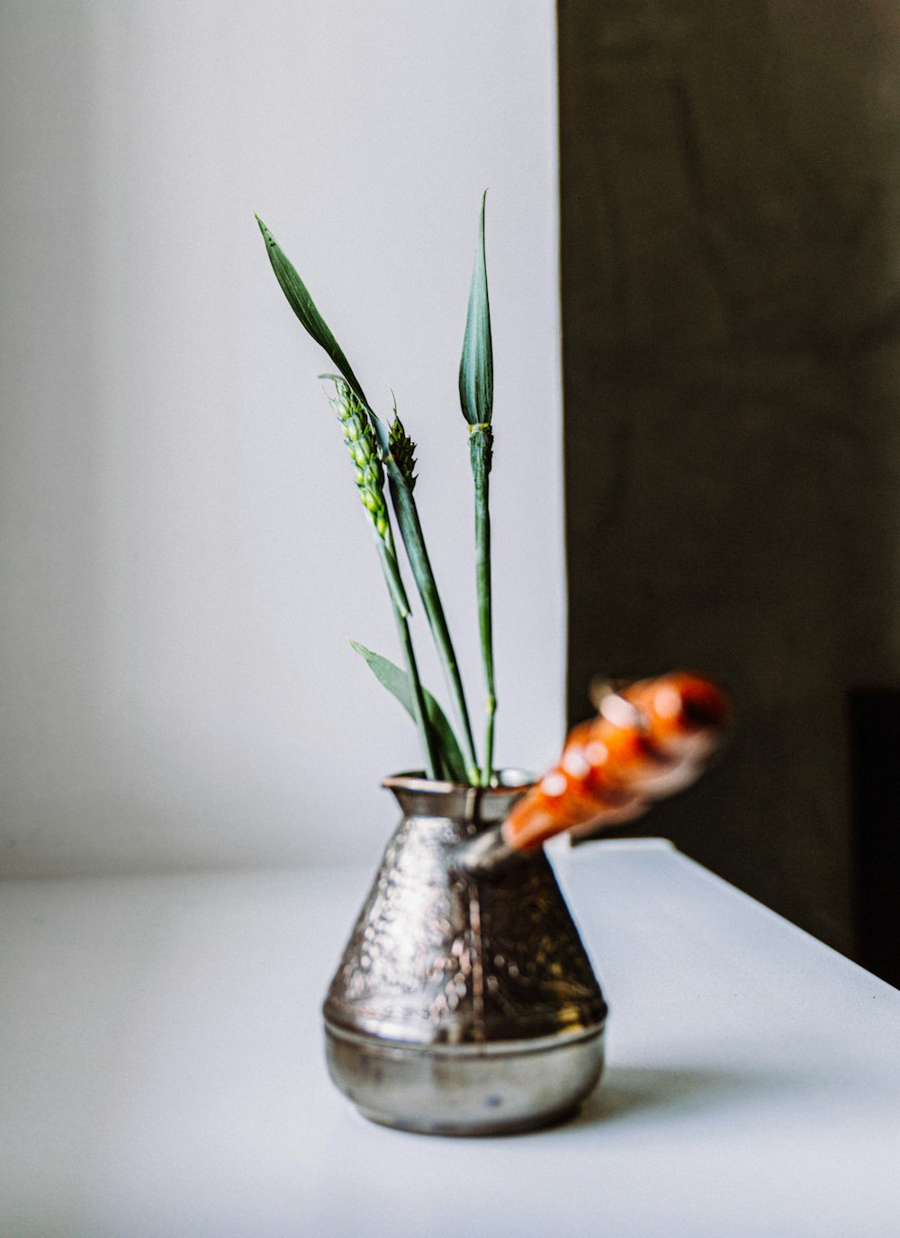 un jarrón de metal con flores sobre una mesa
