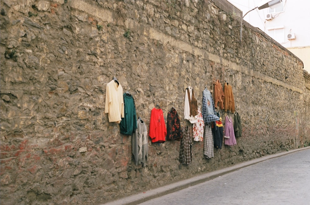 a row of clothes hanging on a stone wall