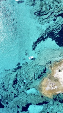 A clear blue sea with a small boat receiving fresh water from a mobile Aquamavi tanker.