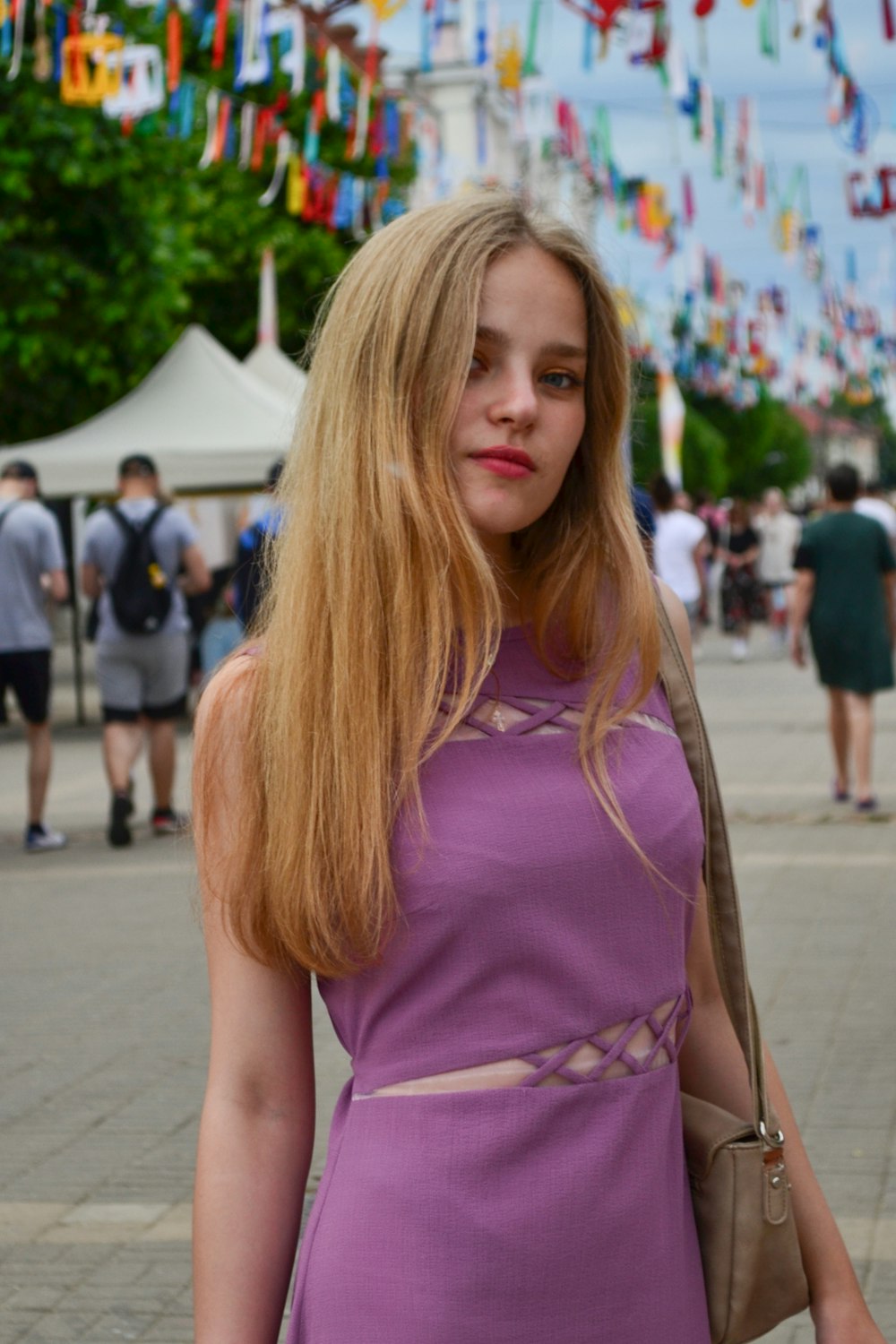 a woman in a purple dress is holding a purse