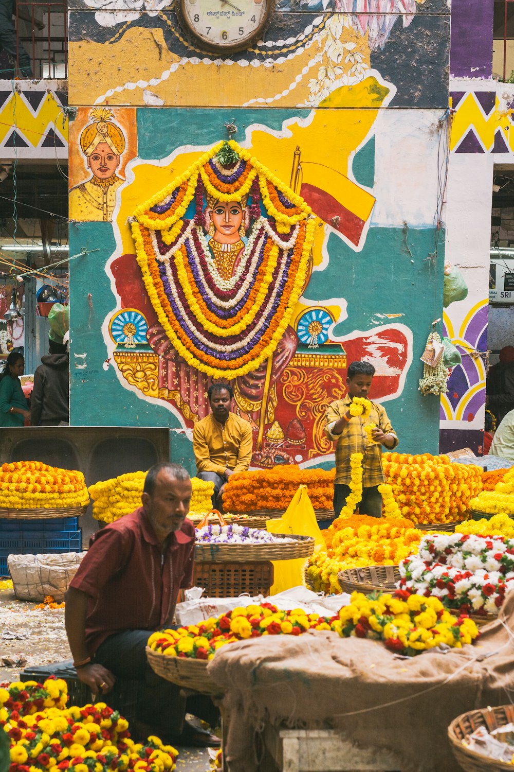 Un hombre sentado frente a una exhibición de fruta