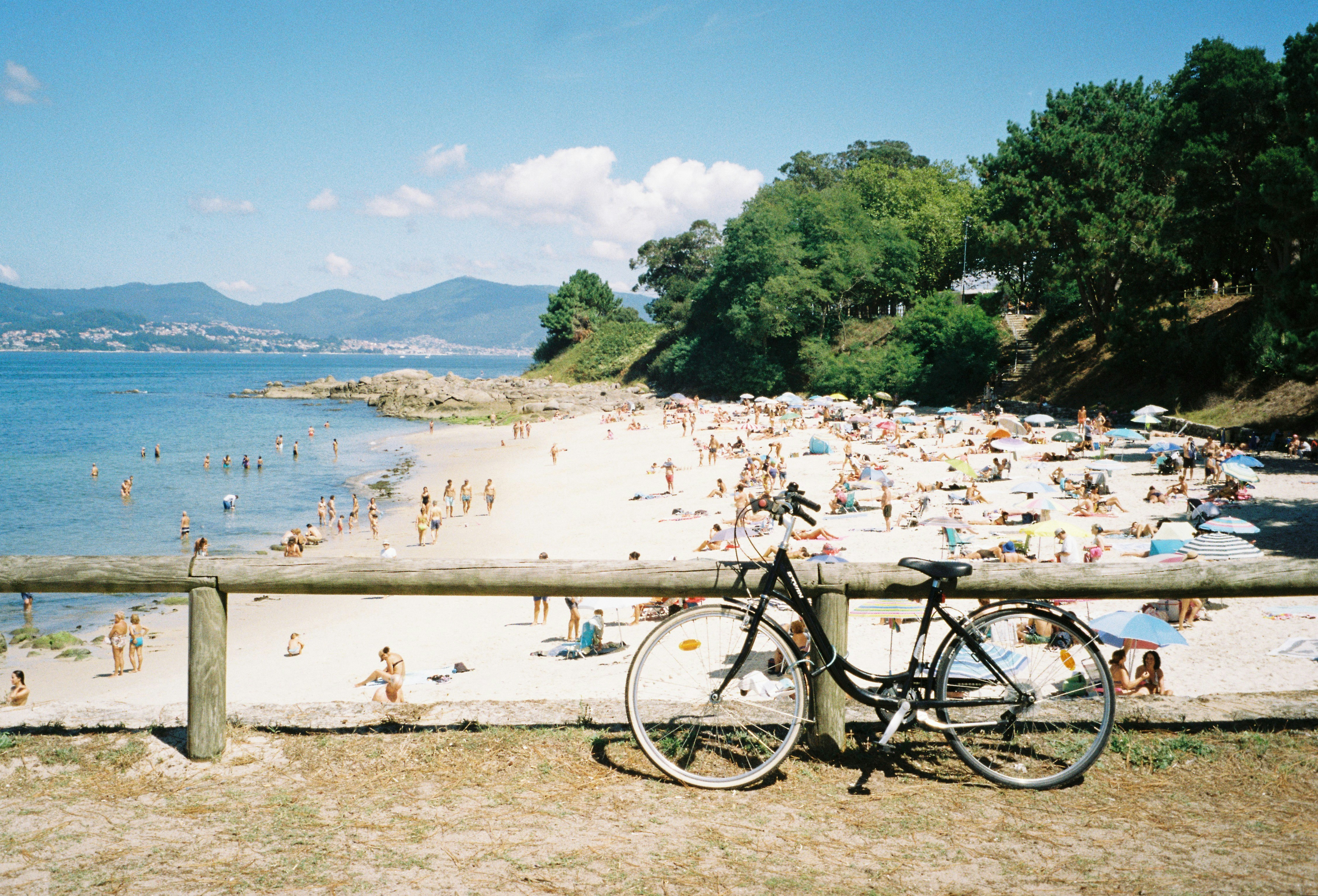 a bicycle parked next to a wooden fence on a beach