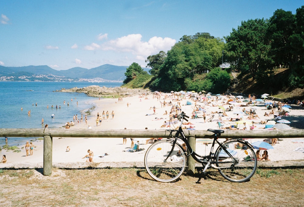 a bicycle parked next to a wooden fence on a beach