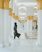a woman in a black and white outfit walking down a hallway