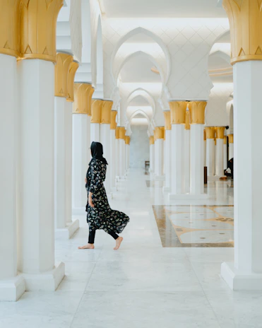 a woman in a black and white outfit walking down a hallway