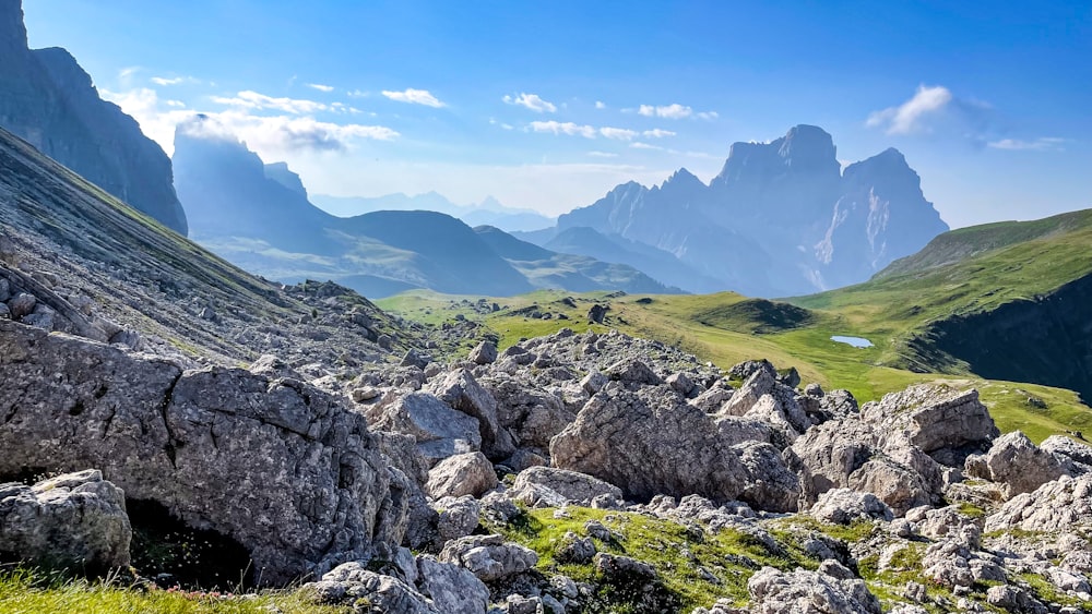 a mountain range with rocks and grass in the foreground