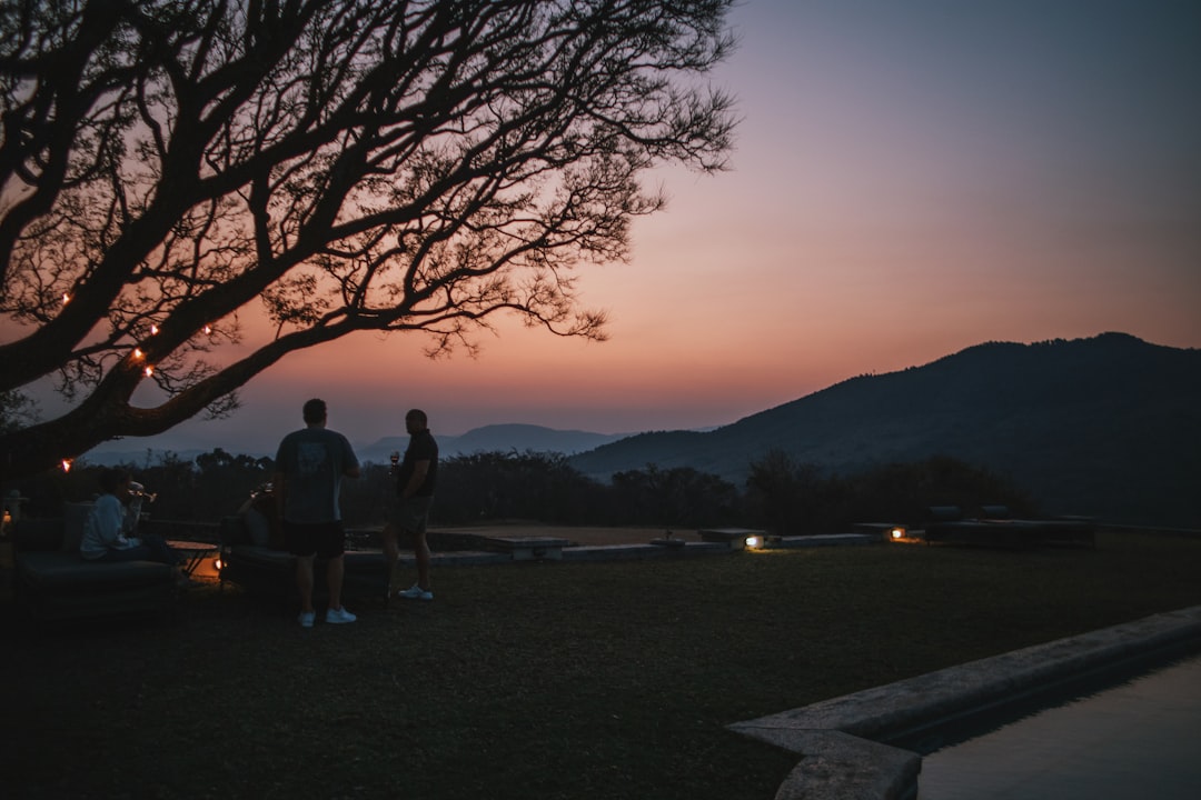 a couple of people standing next to a tree,