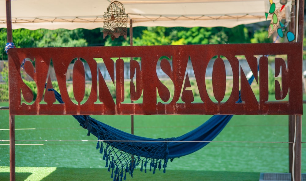 a wooden sign that reads, saone saone with a hammock hanging