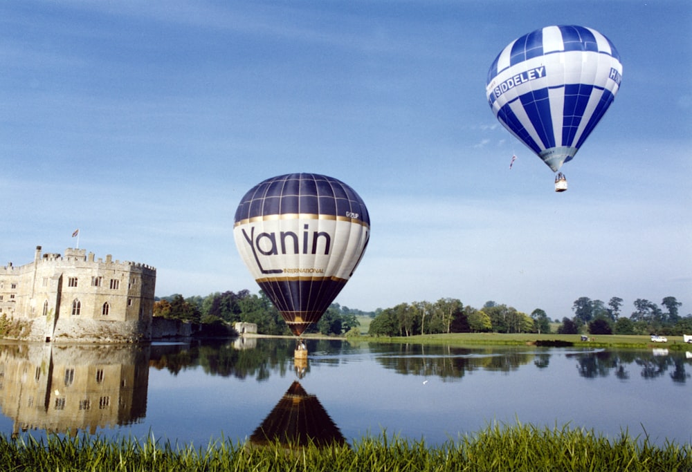 a couple of hot air balloons flying over a lake