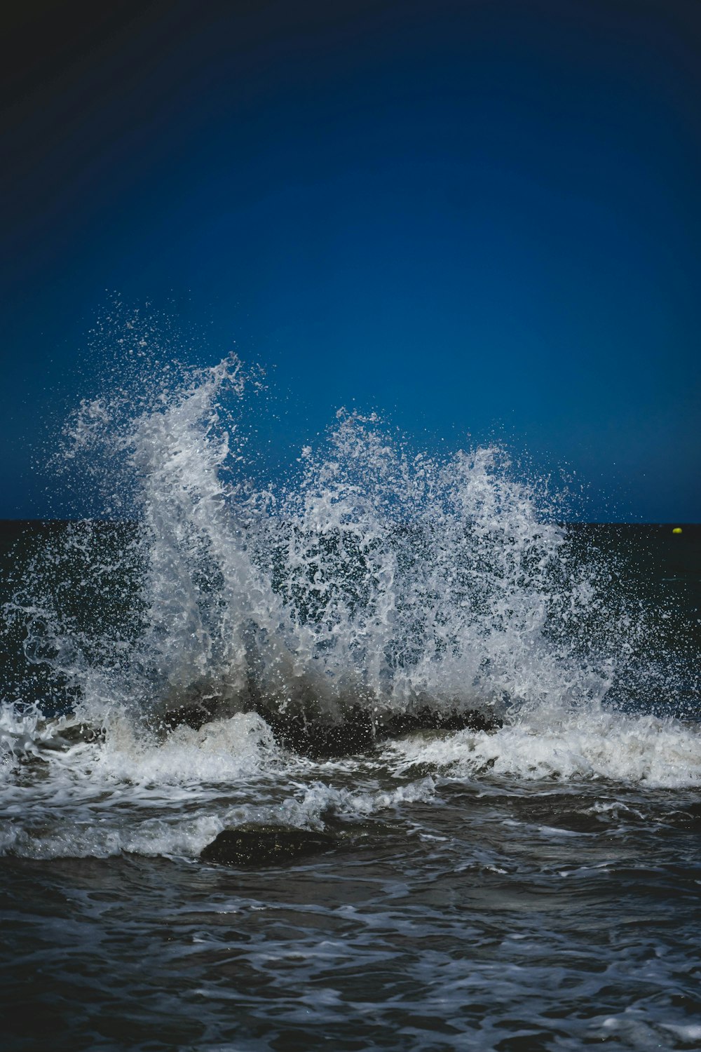 a large wave crashing into the ocean on a sunny day