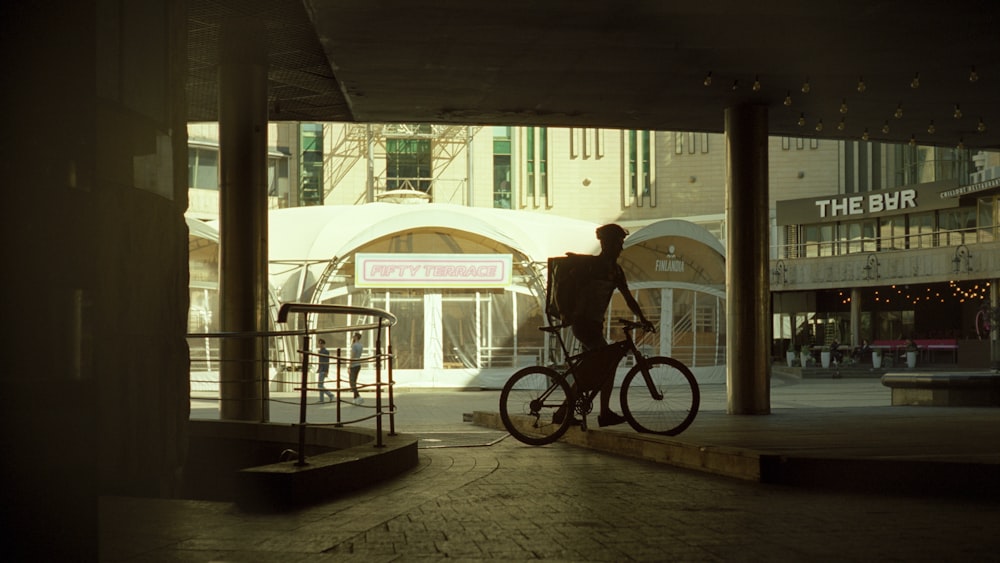 a man riding a bike down a street under a bridge