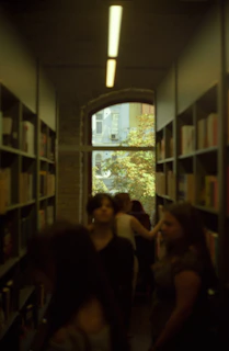 A cinematic shot of the outdoor reading area bathed in soft sand light with people enjoying books under terracotta umbrellas.