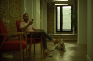 A friendly dog sitting beside a wooden table with a phone.