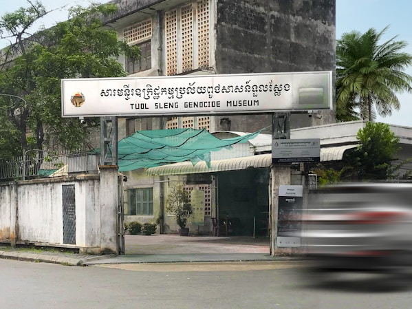 a car driving past a tall building with a sign on it