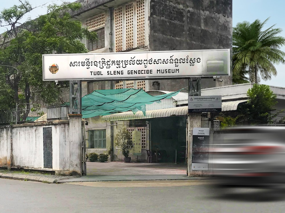 a car driving past a tall building with a sign on it