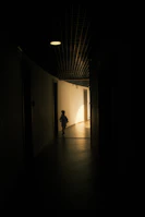 Cinematic shot of a child walking gracefully along a sunlit, spacious corridor with large windows.