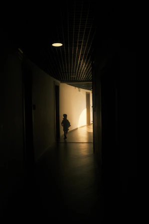 Cinematic shot of a child walking gracefully along a sunlit, spacious corridor with large windows.