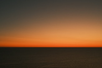 A serene ocean view with a traveler gazing at the horizon during sunset.