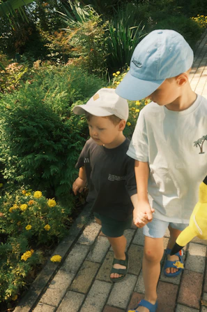 Children smiling and holding hands in a sunny outdoor garden filled with sunflowers.