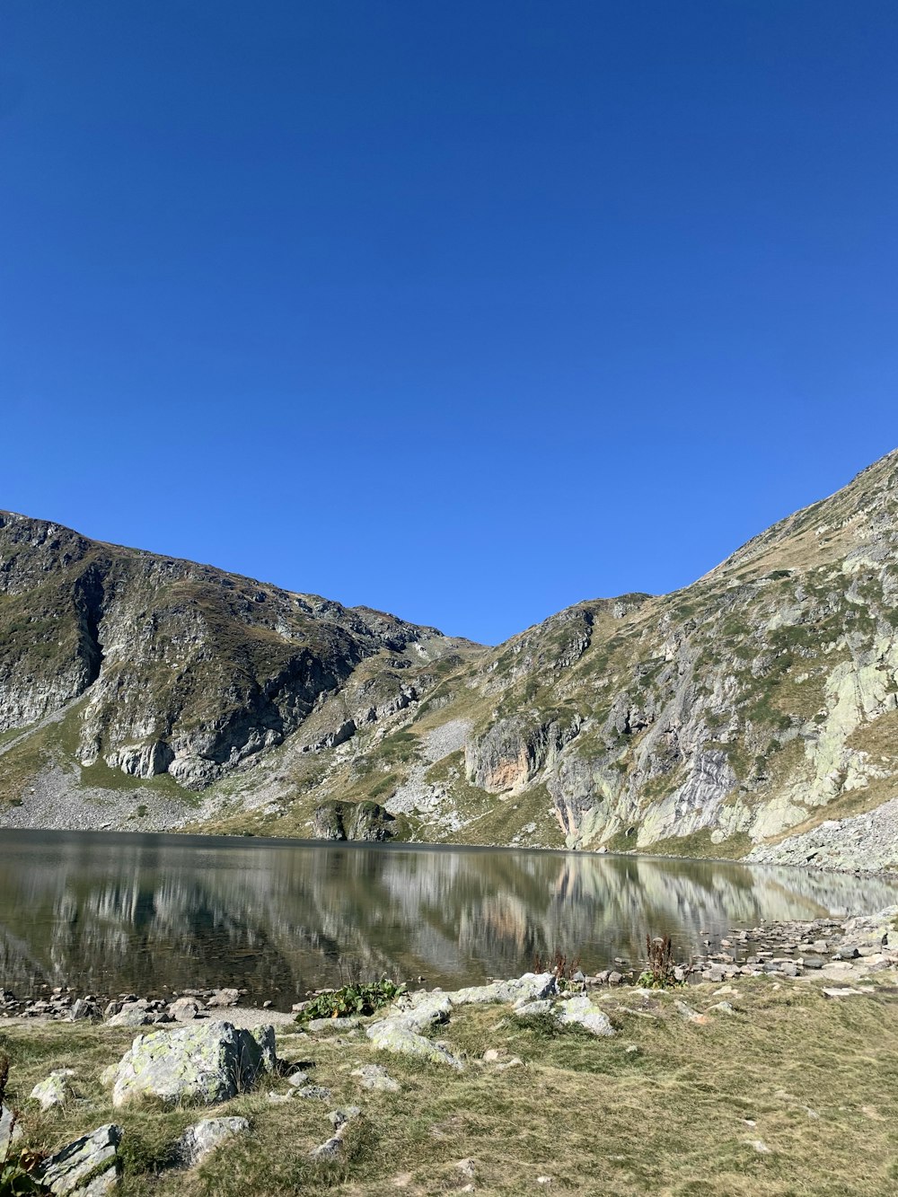 a mountain lake surrounded by grass and rocks