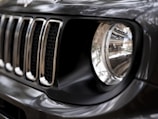 Close-up of a car's headlight and grille under natural light.