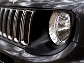 Close-up of a car's headlight and grille under natural light.