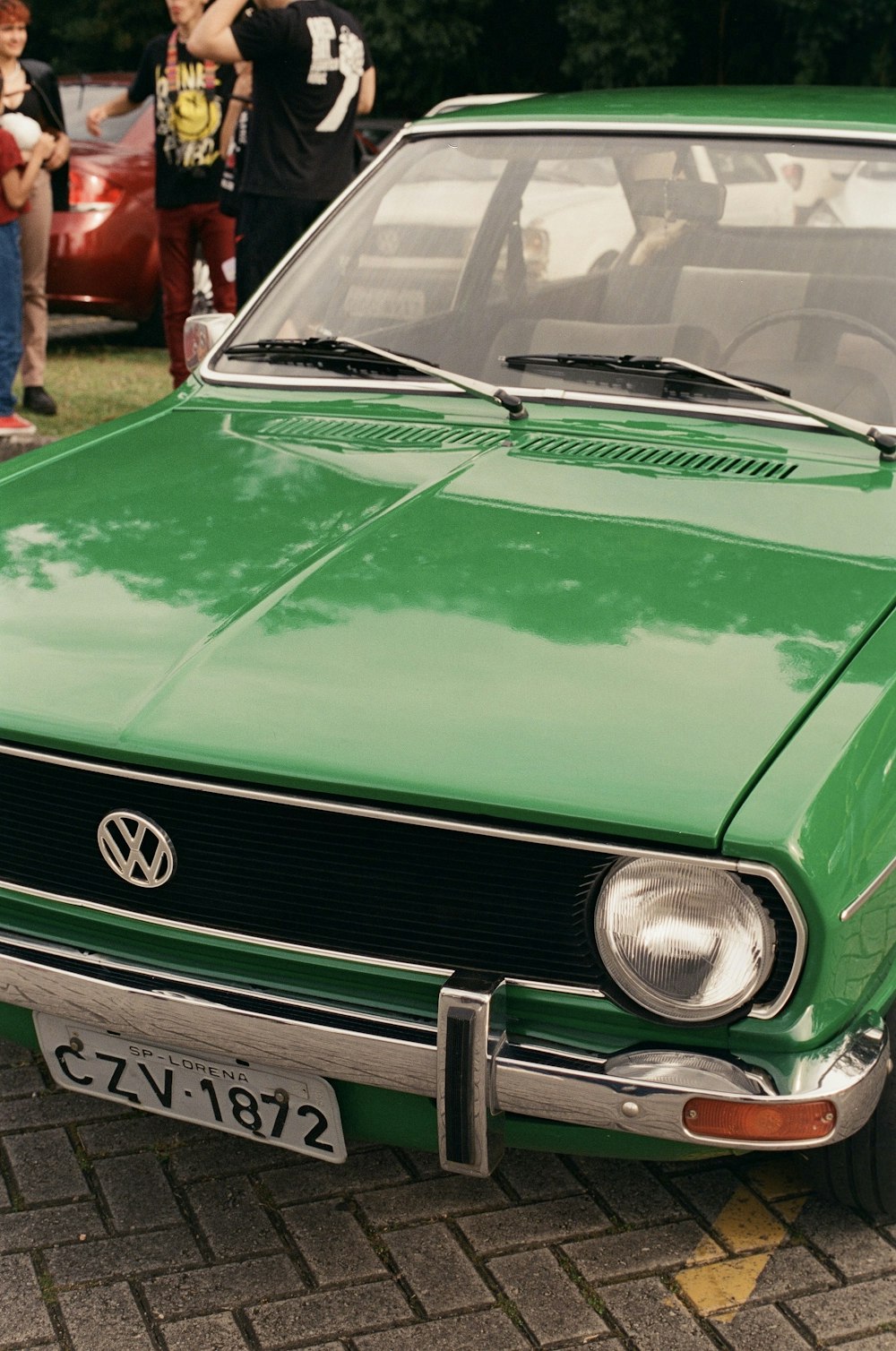 a green car is parked on the side of the road