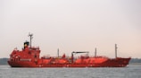 a large red boat floating on top of a body of water