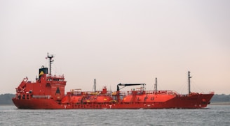 a large red boat floating on top of a body of water