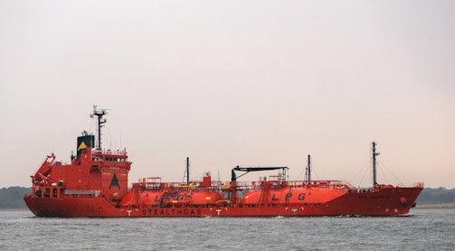 a large red boat floating on top of a body of water
