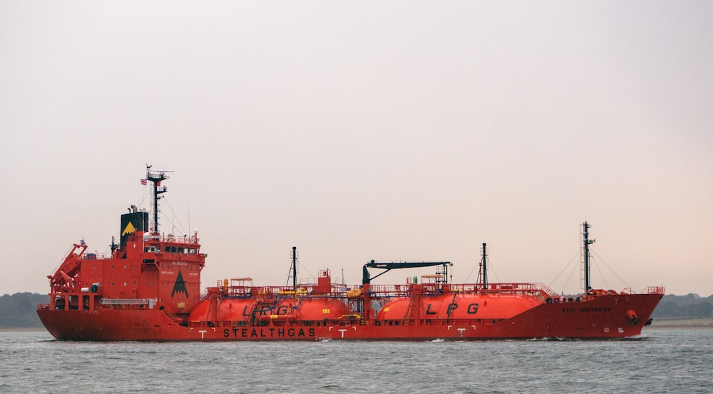 a large red boat floating on top of a body of water