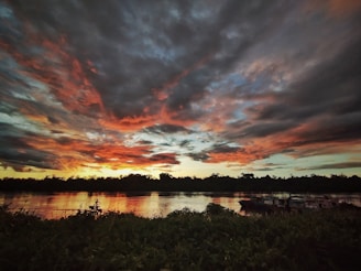 A vibrant sunset over the Kampot river with traditional boats gently floating by.