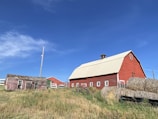 The red barn at Borrelyngvej 15 with fresh hay stacked neatly outside on a bright morning.