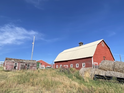 The red barn at Borrelyngvej 15 with fresh hay stacked neatly outside on a bright morning.
