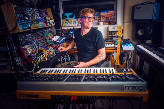 Photo of the artist in a cozy studio setting, surrounded by instruments and recording equipment.