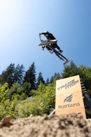 A photographer capturing a cyclist jumping over a ramp during a race