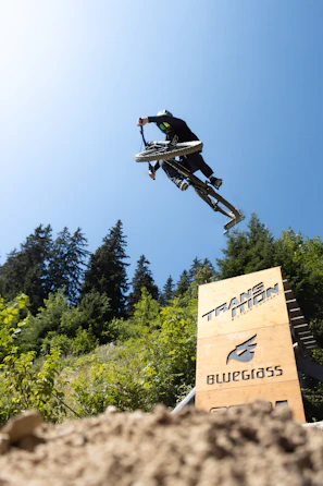 A photographer capturing a cyclist jumping over a ramp during a race