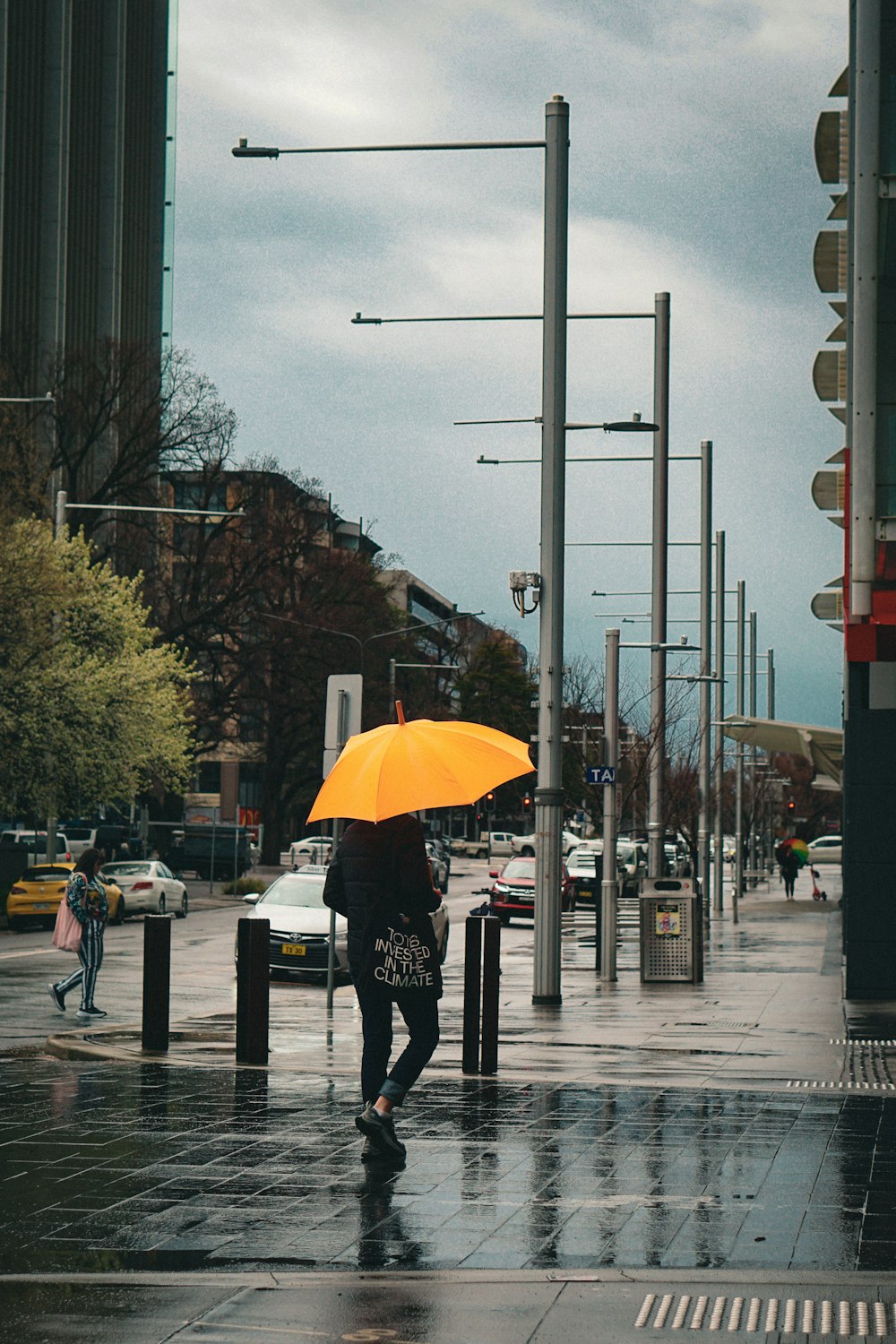 a person walking down a street with a yellow umbrella