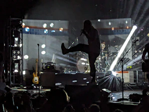 An artist mid-performance, illuminated by dramatic lighting with bold shadows and vibrant energy