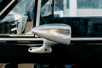 A mechanic carefully inspecting a used side mirror before installation.