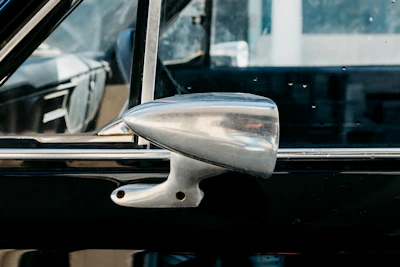 A mechanic carefully inspecting a used side mirror before installation.