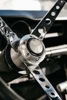 Detail of a vintage car’s steering wheel with a three-spoke design and polished chrome