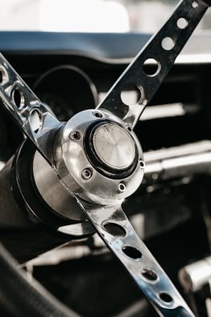 Detail of a vintage car’s steering wheel with a three-spoke design and polished chrome