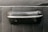 A close-up view of a textured black material featuring a protruding handle-like object, possibly part of a vehicle's interior door panel. The handle has a smooth, polished metallic trim and a black leather-like covering.
