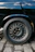 Close-up of shiny tires and rims on a black car parked on a city street.